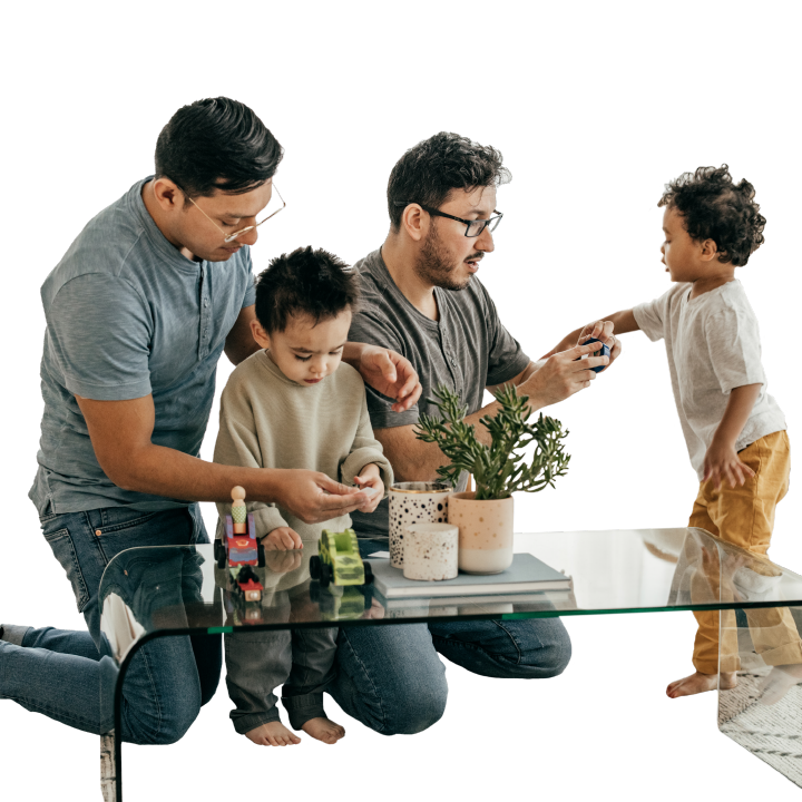 Two fathers and two young boys sitting at a coffee table playing with toys